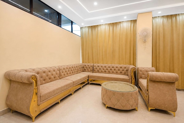 A modern living room with a beige sectional sofa, a round ottoman, and a small table.