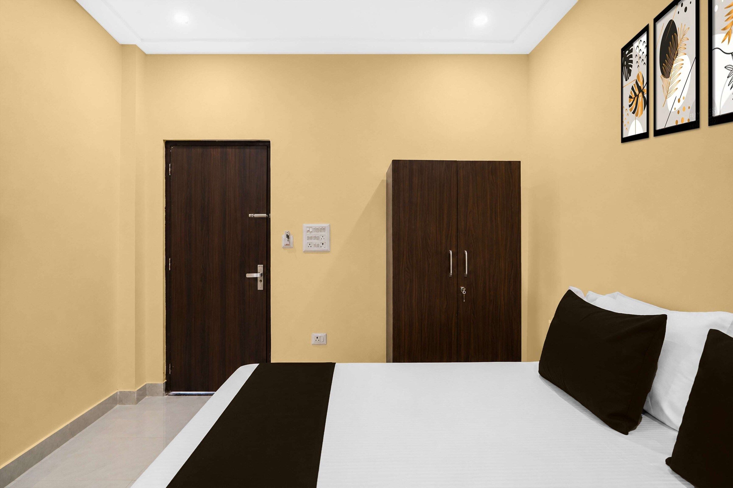 A hotel room with a bed, two wardrobes, a door, and a wall socket.