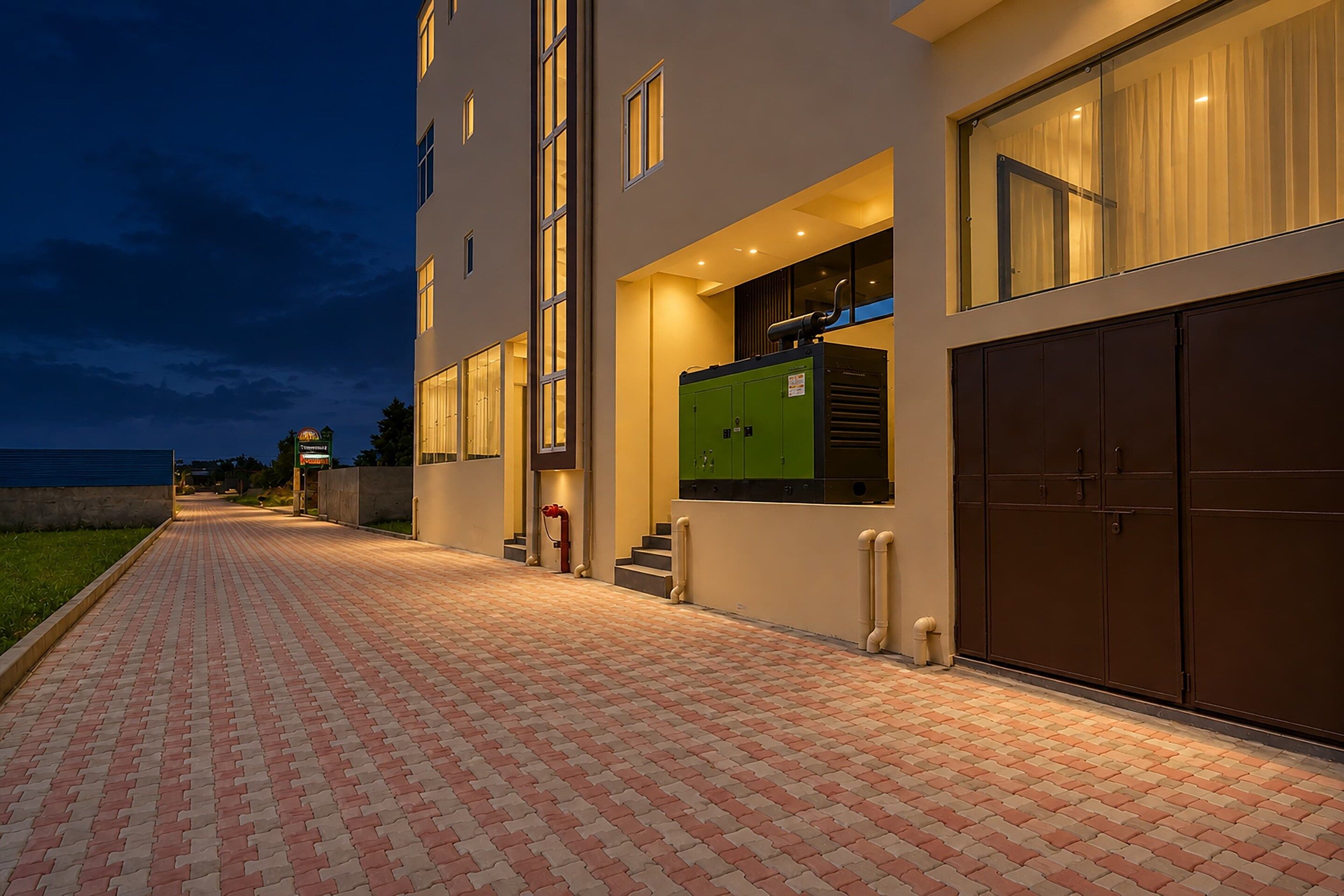 A building with a brick pathway leading to a set of stairs and a green utility room.