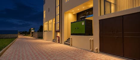 A building with a brick pathway leading to a set of stairs and a green utility room.