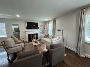 Ein modernes Wohnzimmer mit Kamin, einer Couch, einem Couchtisch und einem Fernseher.