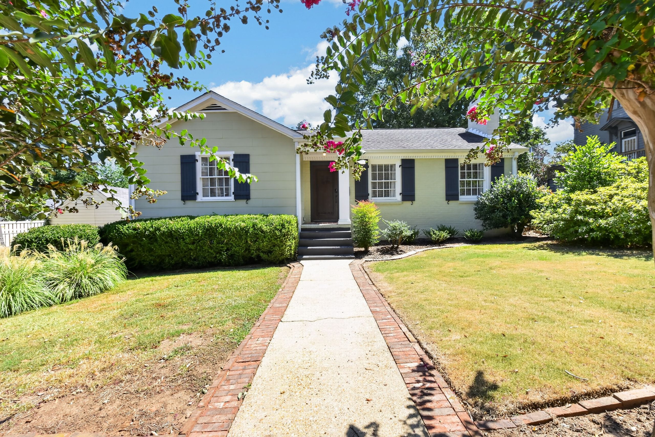A single-story house with a front entrance, a brick pathway leading to the door, and a well-maintained lawn.