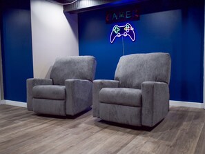 Two grey armchairs in a room with a blue accent wall and a neon sign reading 'GAMER' with a game controller symbol. - Private Basement Retreat in South Bend 10 min from Notre Dame (South Bend)