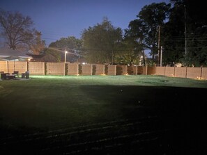 Ein eingezäunter Garten mit Rasen und Gartenmöbeln.