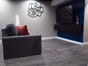 Ein modernes Wohnzimmer mit einem grauen Sofa, einem Wanddekor und einer blauen Akzentwand.