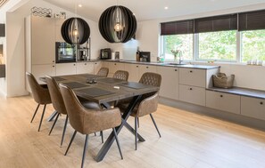 A modern kitchen with a dining area, featuring a large island, pendant lighting, and a view of the outdoors. - 3 bedroom amazing home in Ebeltoft (Ebeltoft)