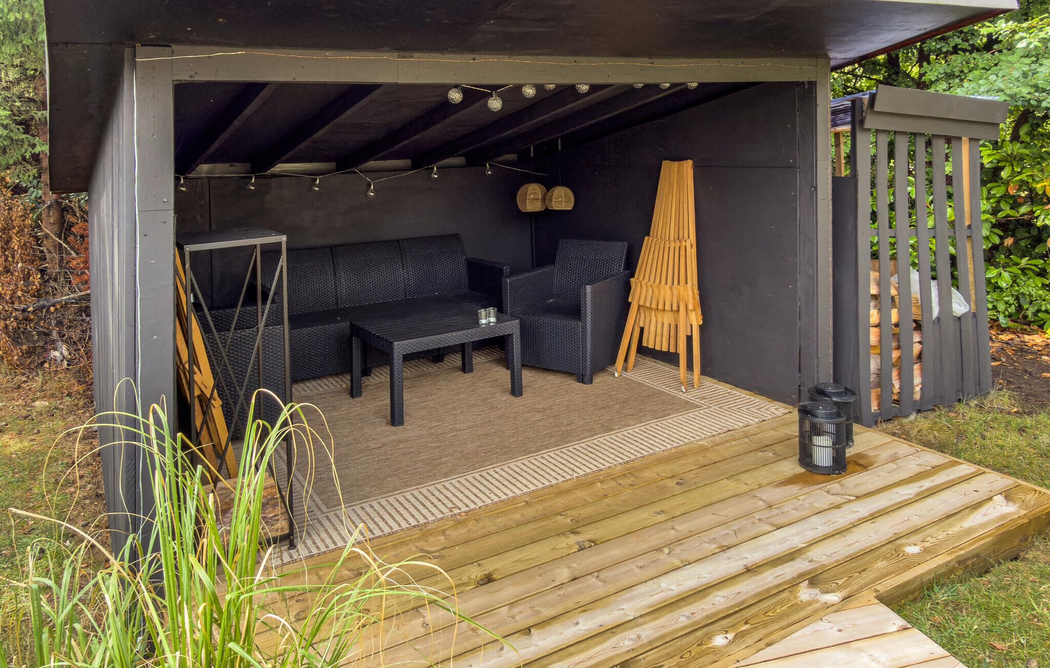 Een terras met een houten dek, een bank, een tafel en een stoel.
