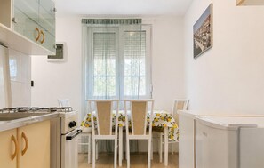 A compact kitchen with a gas stove, a refrigerator, and a dining area with two chairs and a table. - Beautiful apartment in Kavran with WiFi (Kavran)