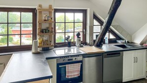 Une cuisine équipée d’un four encastré, d’un évier et d’une fenêtre donnant sur l’extérieur.