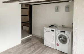 A laundry room with two front-loading washing machines, a wooden floor, and a white wall. - 1 bedroom lovely apartment in Kalkhorst (Kalkhorst)