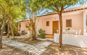 A courtyard with a dining area, a white building with a tiled roof, and a wooden door. - 2 bedroom beautiful home in Nicotera Marina (Nicotera Marina)
