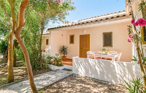 A house with a tiled roof, a wooden door, and a small garden with a table and chairs.