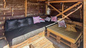 En rustik trästuga med en svart lädersoffa, en vadderad bänk och dekorativa kuddar.
