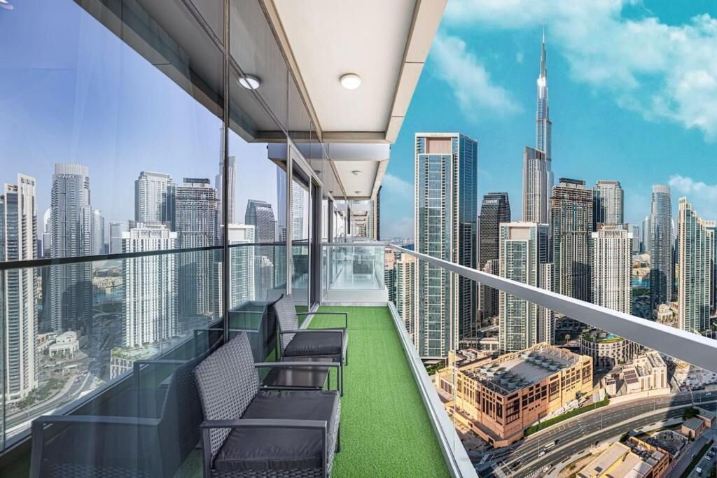 Ein Balkon mit Stadtblick, Glasgeländern und Sitzgelegenheit im Freien.