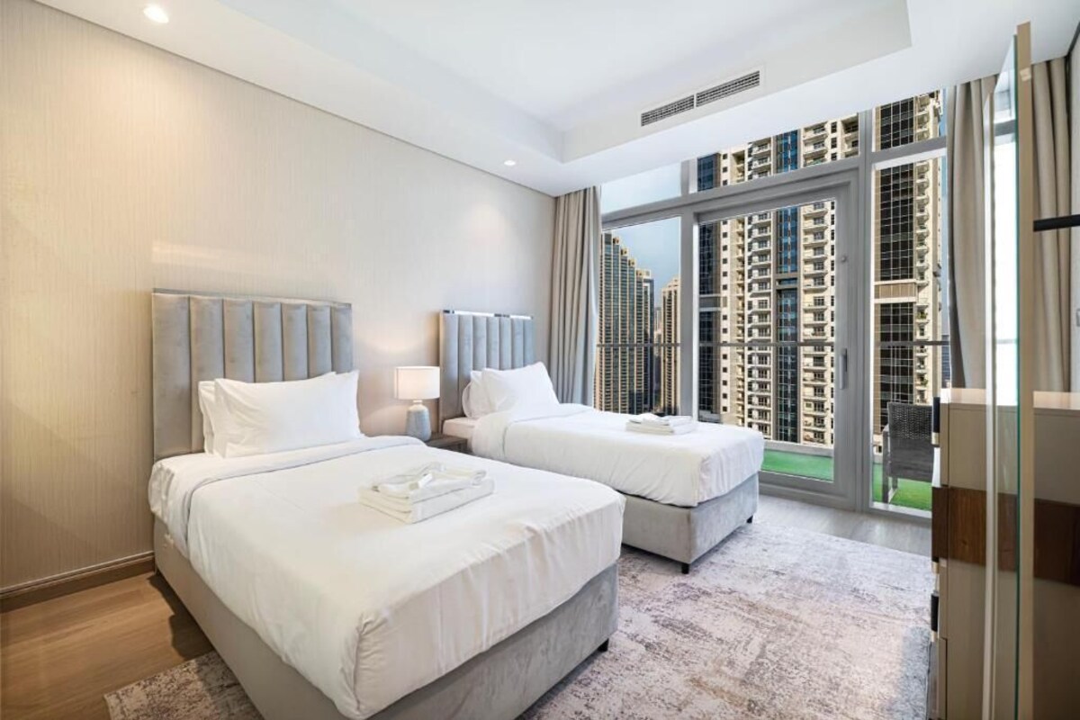 Ein Hotelzimmer mit zwei Betten, einem großen Fenster mit Blick auf die Stadt und einem modernen Design.