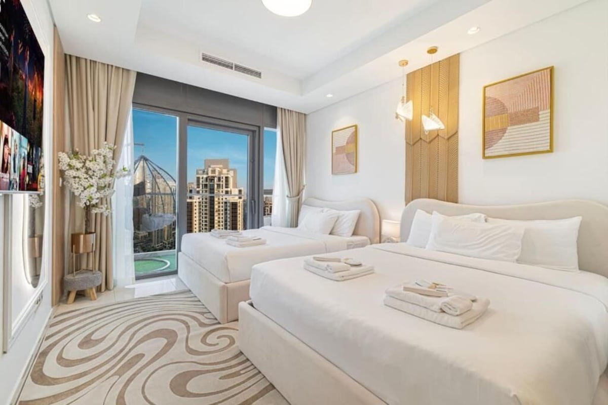 Ein Hotelzimmer mit zwei Betten, einem großen Fenster und Stadtblick sowie einem modernen Design.