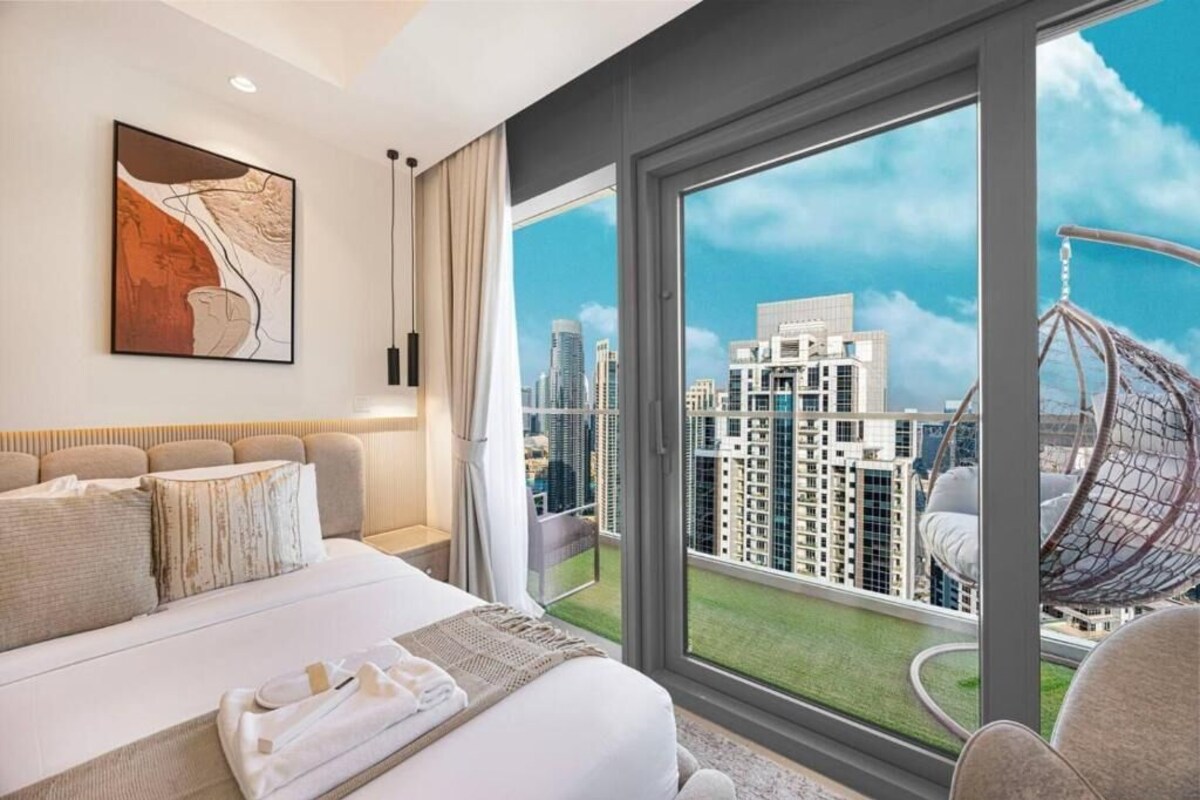 Ein Hotelzimmer mit einem großen Bett, Blick auf die Stadt, einem Hängekorbstuhl und einem Bild an der Wand.