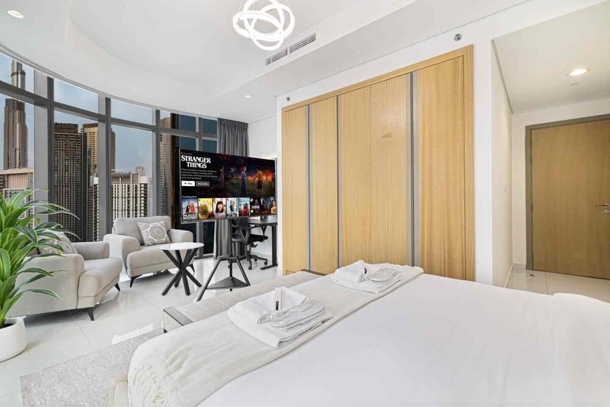 Ein modernes Hotelzimmer mit einem großen Bett, einem Schreibtisch, einem Fernseher und Blick auf die Stadt.