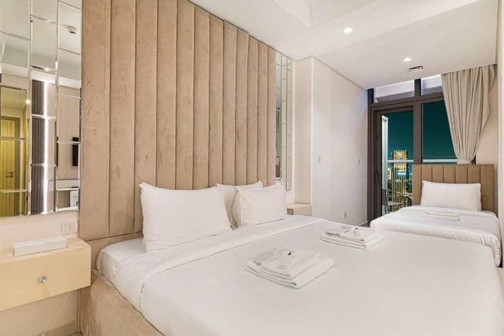 Ein Hotelzimmer mit zwei Betten, einem großen Spiegel, einer Wand aus Holzpaneelen und Blick nach draußen.