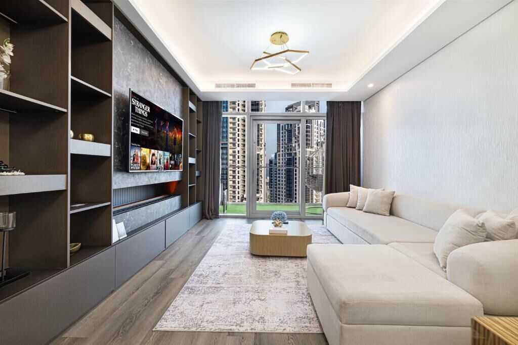 A modern living room with a sofa, a coffee table, and a TV mounted on the wall.