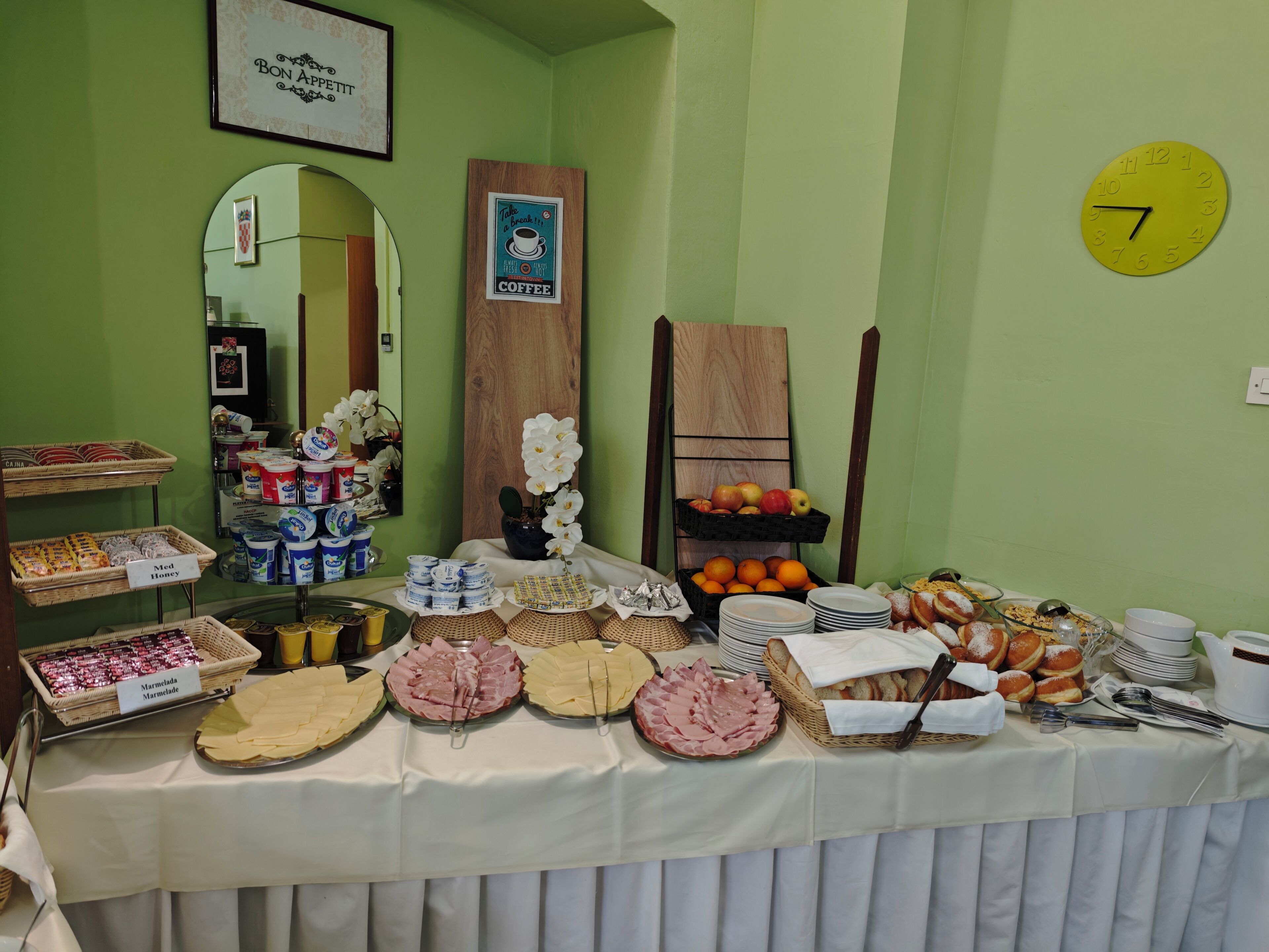 Un buffet de petit-déjeuner proposant divers plats et une horloge au mur.
