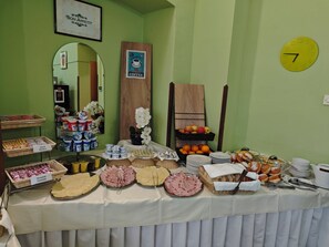 A breakfast buffet with various food items and a clock on the wall. - Hostel Veli Jože (Pula)