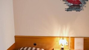 Ein Hotelzimmer mit kariertem Bettbezug, einer Nachttischlampe, einem Nachttisch und einem an der Wand hängenden Kunstwerk.