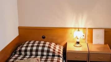 Habitación de hotel con colcha a cuadros, lámpara de noche, mesita de noche y una obra de arte colgada en la pared.