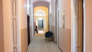 Ein Hotelgang mit Streifenmuster-Teppich, weißen Wänden und Türen an beiden Seiten.