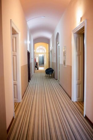 A hotel hallway with a striped carpet, white walls, and doors on either side.