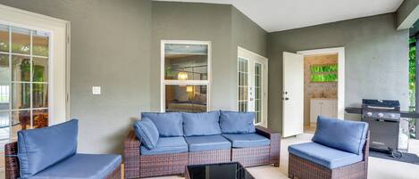 A covered patio area with wicker furniture and a grill.