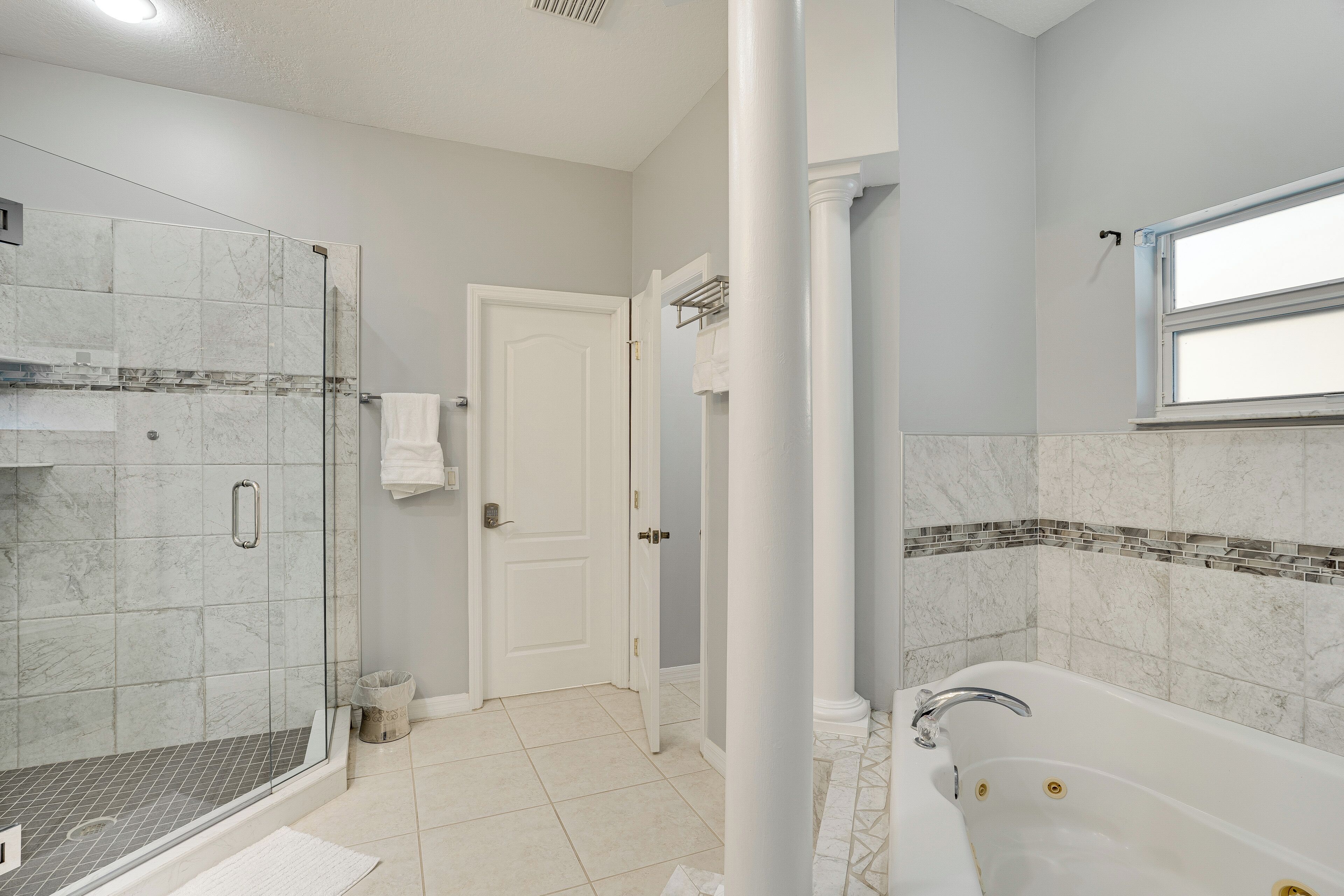 A bathroom with a shower, a bathtub, and a door.