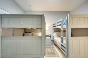 A room with bunk beds, a bedside table, and a lamp. - Heated Pool & Lanai Cookouts! Cape Coral Getaway (Cape Coral)