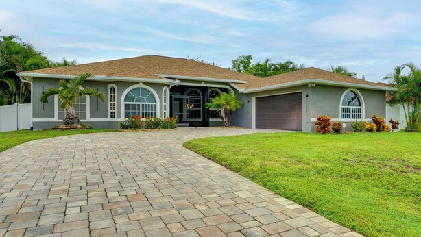 A single-story house with a paved driveway leading to a garage. - Heated Pool & Lanai Cookouts! Cape Coral Getaway (Cape Coral)