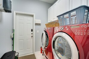 A laundry room with a red washing machine, a white door, and a green broom. - Heated Pool & Lanai Cookouts! Cape Coral Getaway (Cape Coral)