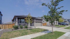 A residential house with a stone facade, a garage, and a well-maintained lawn. - Private Yard w/ Patio! Modern Commerce City Gem (Commerce City)