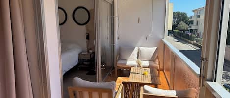 A balcony with a wooden table, two chairs, and a sofa.