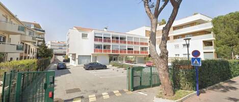 Un edificio residencial de varios pisos con un estacionamiento al frente.