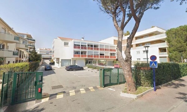 A multi-story residential building with a parking area in front. - Air-conditioned apartment with a pool, 200 meters from the ocean - Secure residential complex. (Fréjus)