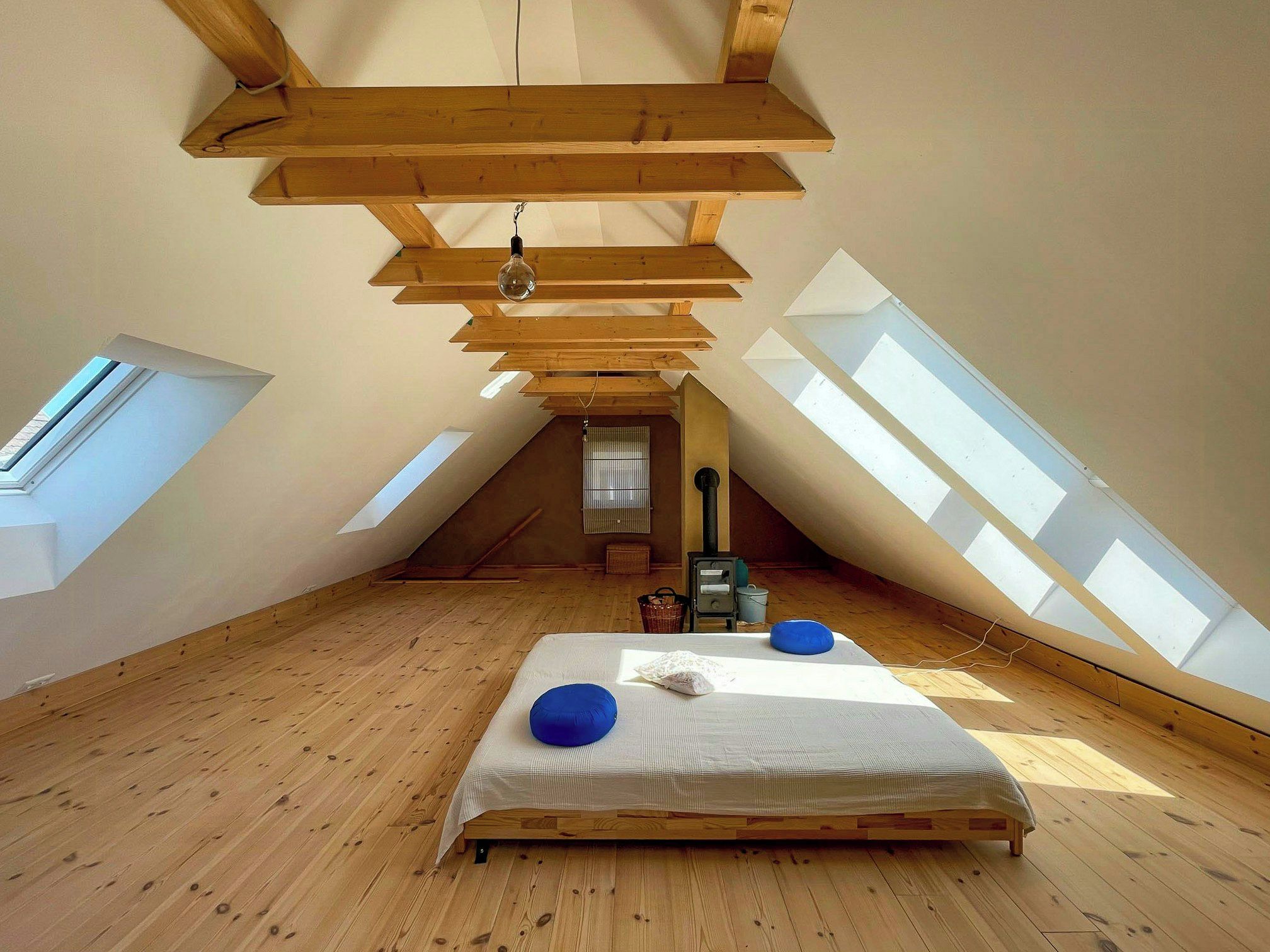 Un dormitorio en ático con techos altos, tragaluces, una cama y un radiador.