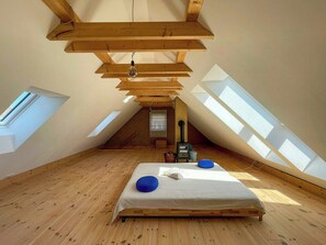 A high-ceilinged attic bedroom with skylights, a bed, and a radiator. - Quiet studio retreat with a peaceful garden (Wenzlow OT Boecke)