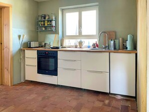 A compact kitchen with a built-in oven, a sink, and a window above the countertop. - Quiet studio retreat with a peaceful garden (Wenzlow OT Boecke)