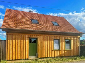 A small wooden house with a sloped red-tiled roof, two windows, and a green door. - Quiet studio retreat with a peaceful garden (Wenzlow OT Boecke)