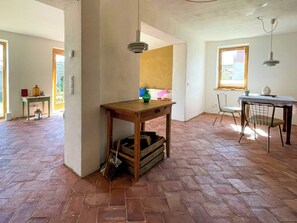 A spacious room with a herringbone floor pattern, a wooden table with a drawer, a chair, and a hanging light fixture. - Quiet studio retreat with a peaceful garden (Wenzlow OT Boecke)
