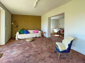 Ein geräumiger Wohnbereich mit einer Couch, einem Sessel, einem Esstisch und einer Lampe.