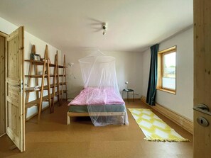 Quarto com cama, escada, mesa de cabeceira, janela e porta.