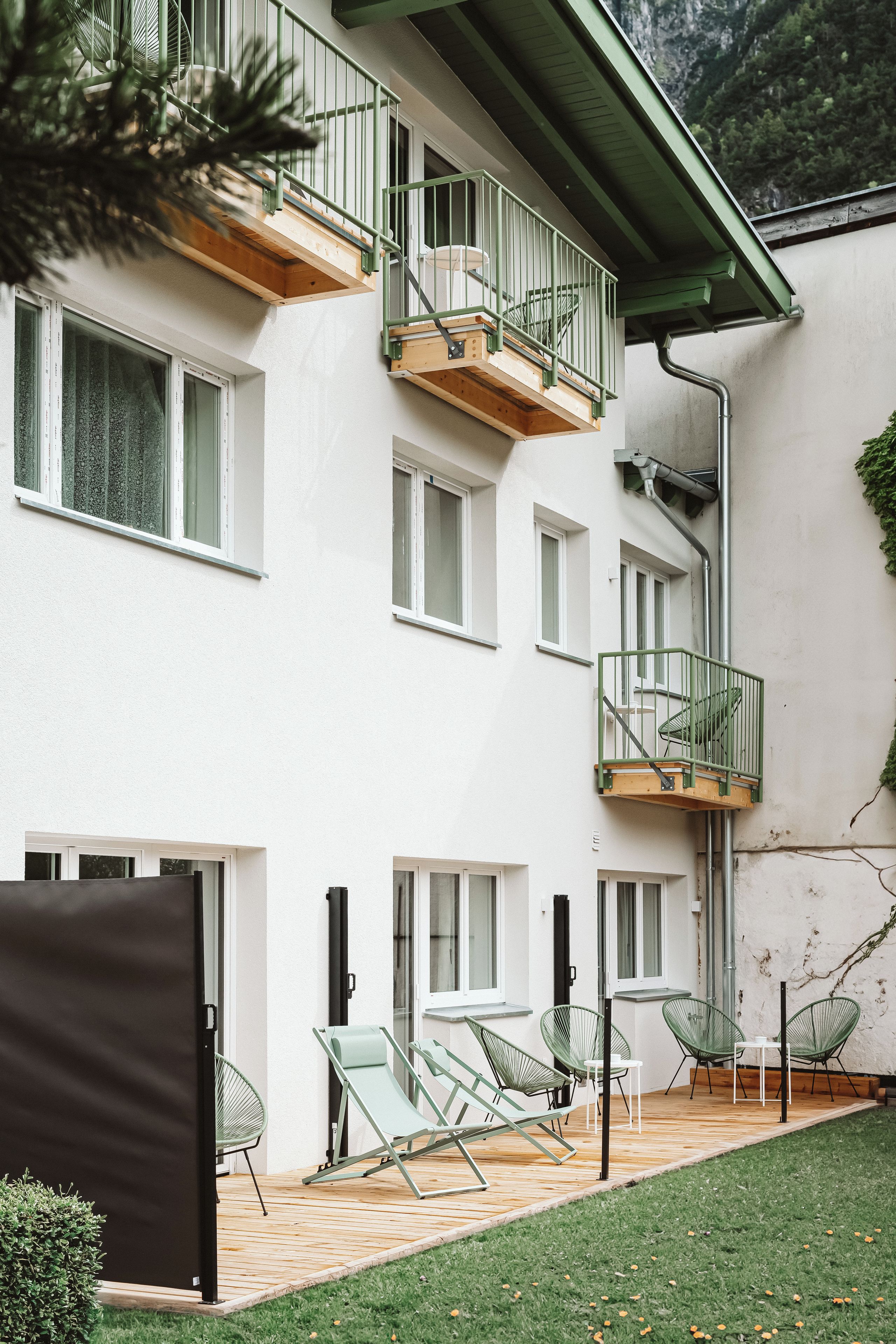 A multi-story building with a balcony, outdoor seating, and a grassy area.