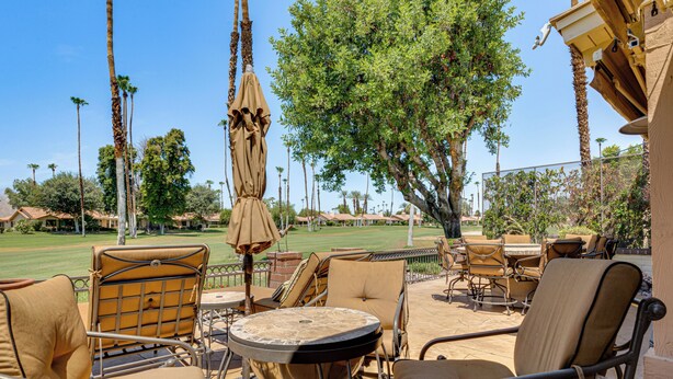 Eine Terrasse im Freien mit Sitzgelegenheit, einem Tisch und einem Sonnenschirm.