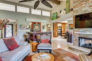 A spacious living area with a fireplace, a sofa, a coffee table, and a dining area with a bar. - Extended Getaway in the Heart of Palm Desert (Palm Desert)