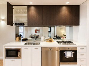 A modern kitchen with built-in appliances, a dishwasher, and a stove. - Heart of Doncaster 1BR Apt with  Wi-FI Parking (Doncaster)